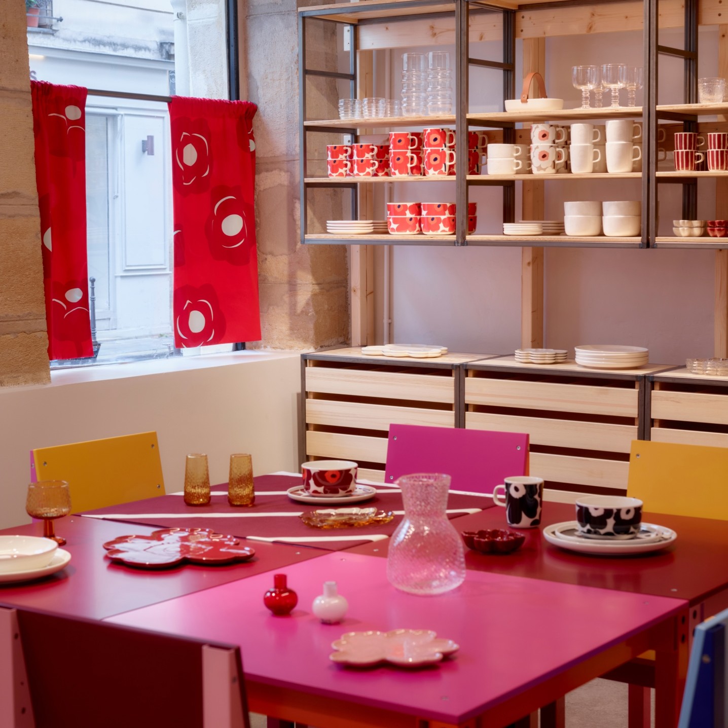 Display of Marimekko home items such as mugs, plates, tumblers.