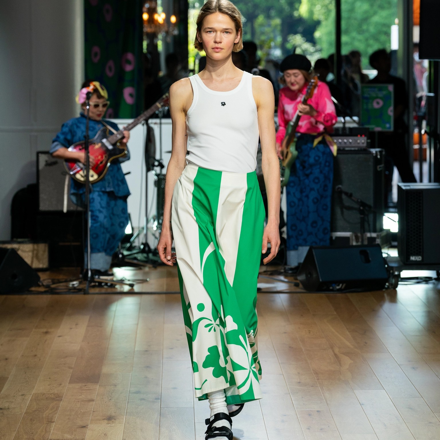 Model wearing white top with Unikko pattern and green-white skirt.