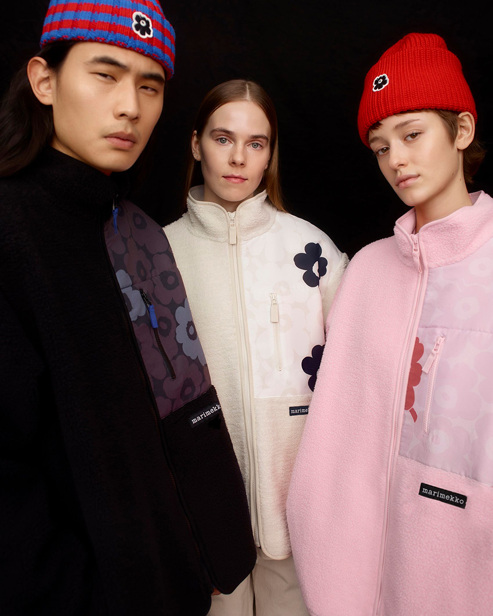 Three models wearing Marimekko Kioski fleece shirts in black, white and pink Mini Unikko print.