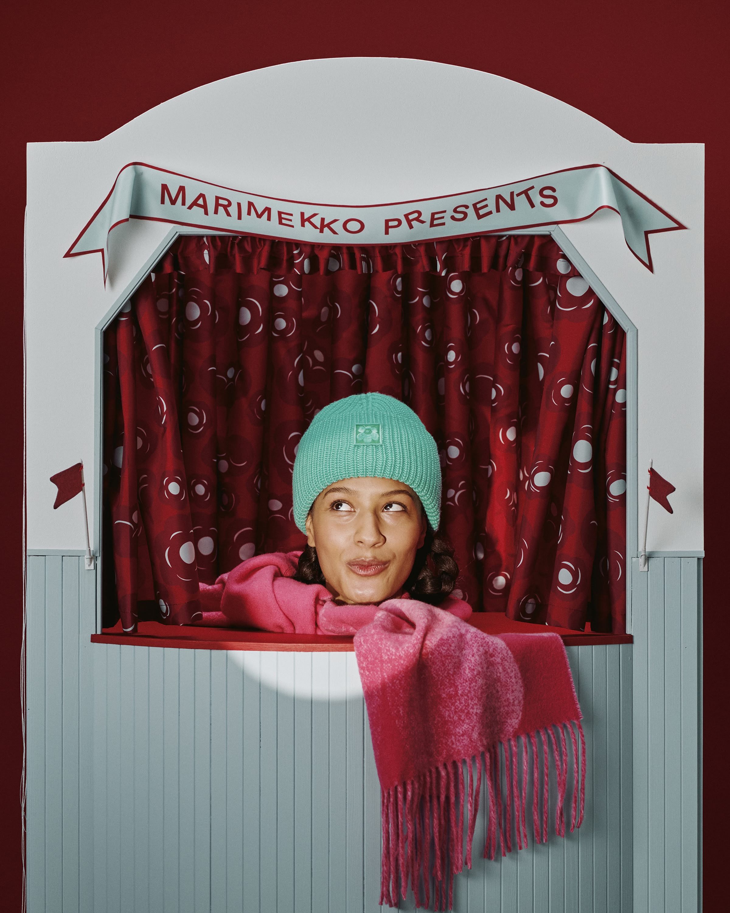 Mallilla päällä vihreä pipo ja punainen huivi