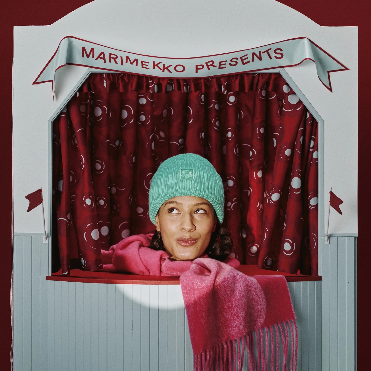 Mallilla päällä vihreä pipo ja punainen huivi