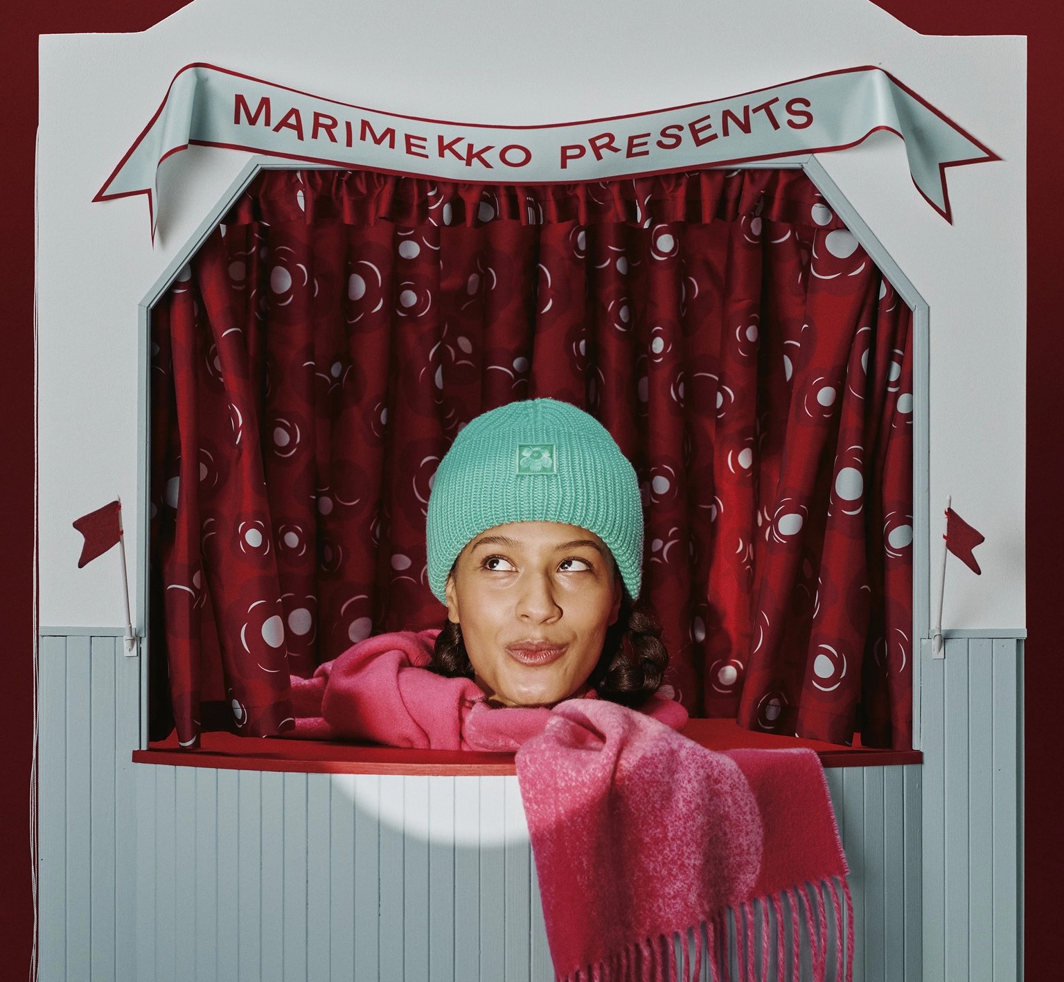 Mallilla päällä vihreä pipo ja punainen huivi