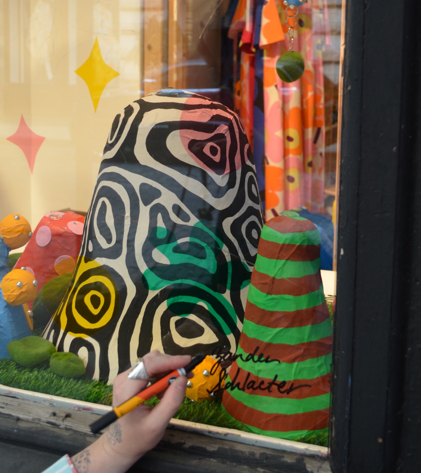 Zander Schlacter signing his artwork in the window of a New York store.