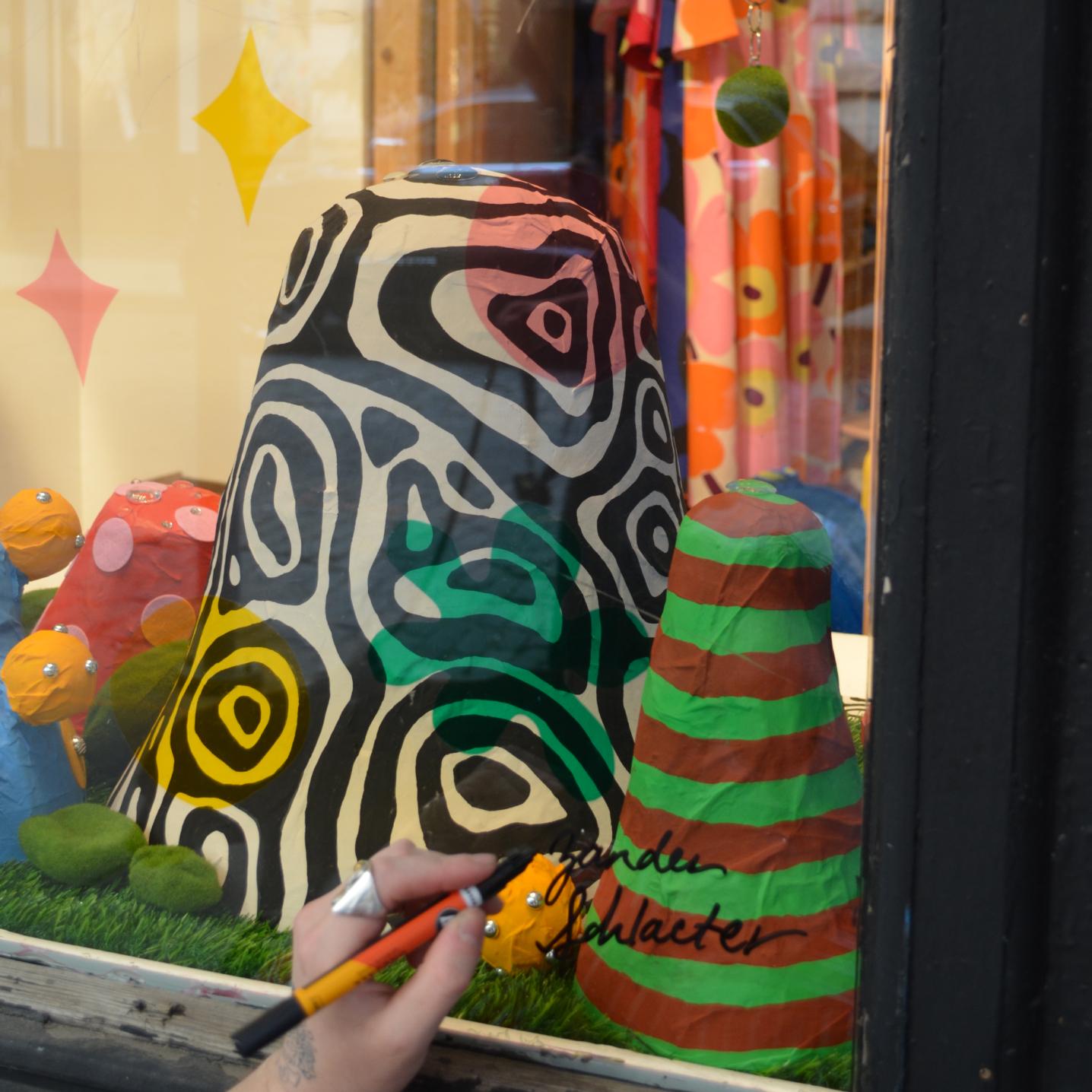 Zander Schlacter signing his artwork in the window of a New York store.
