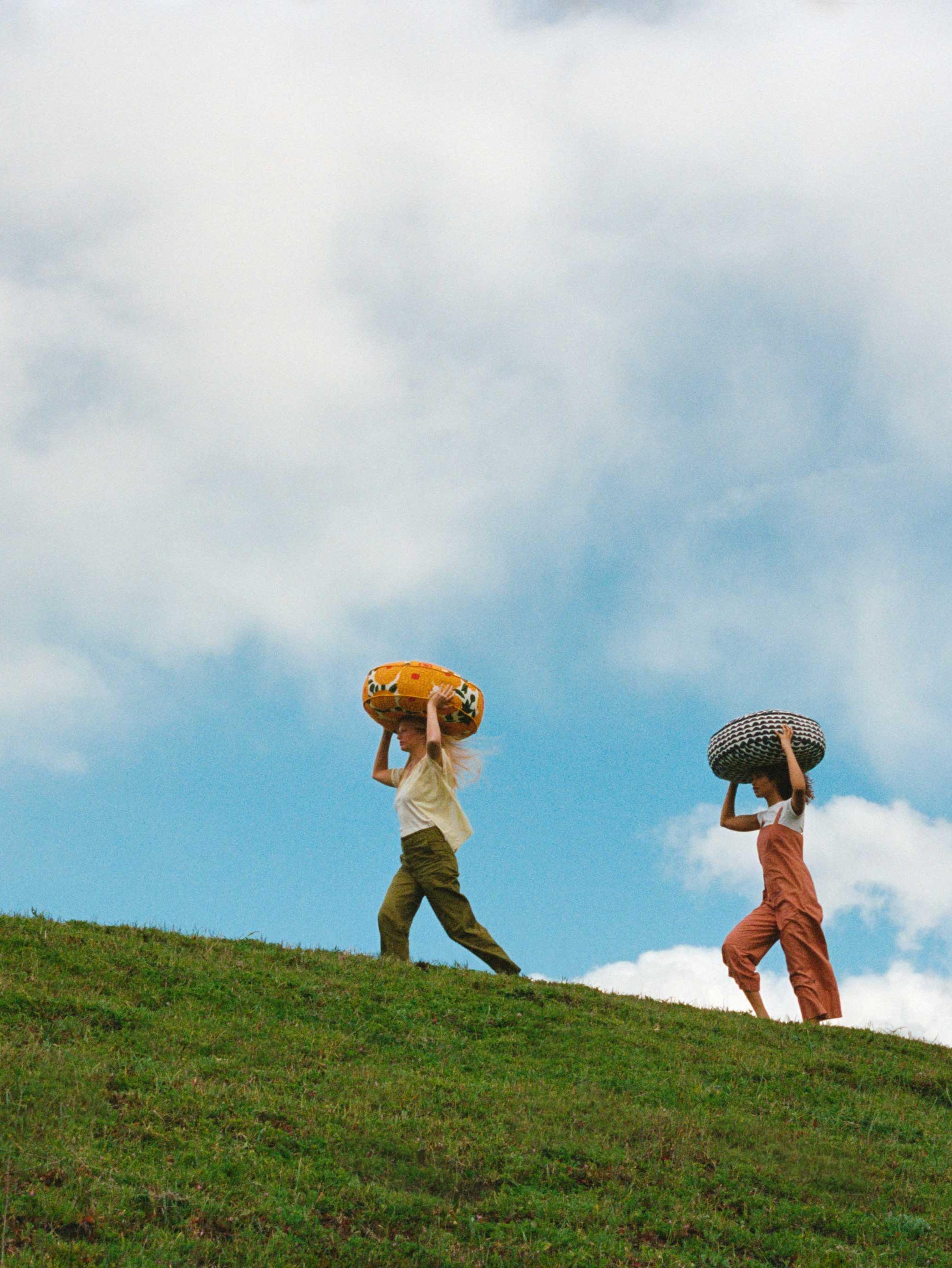 Models carrying West Elm and Marimekko collaboration cushions in the green field