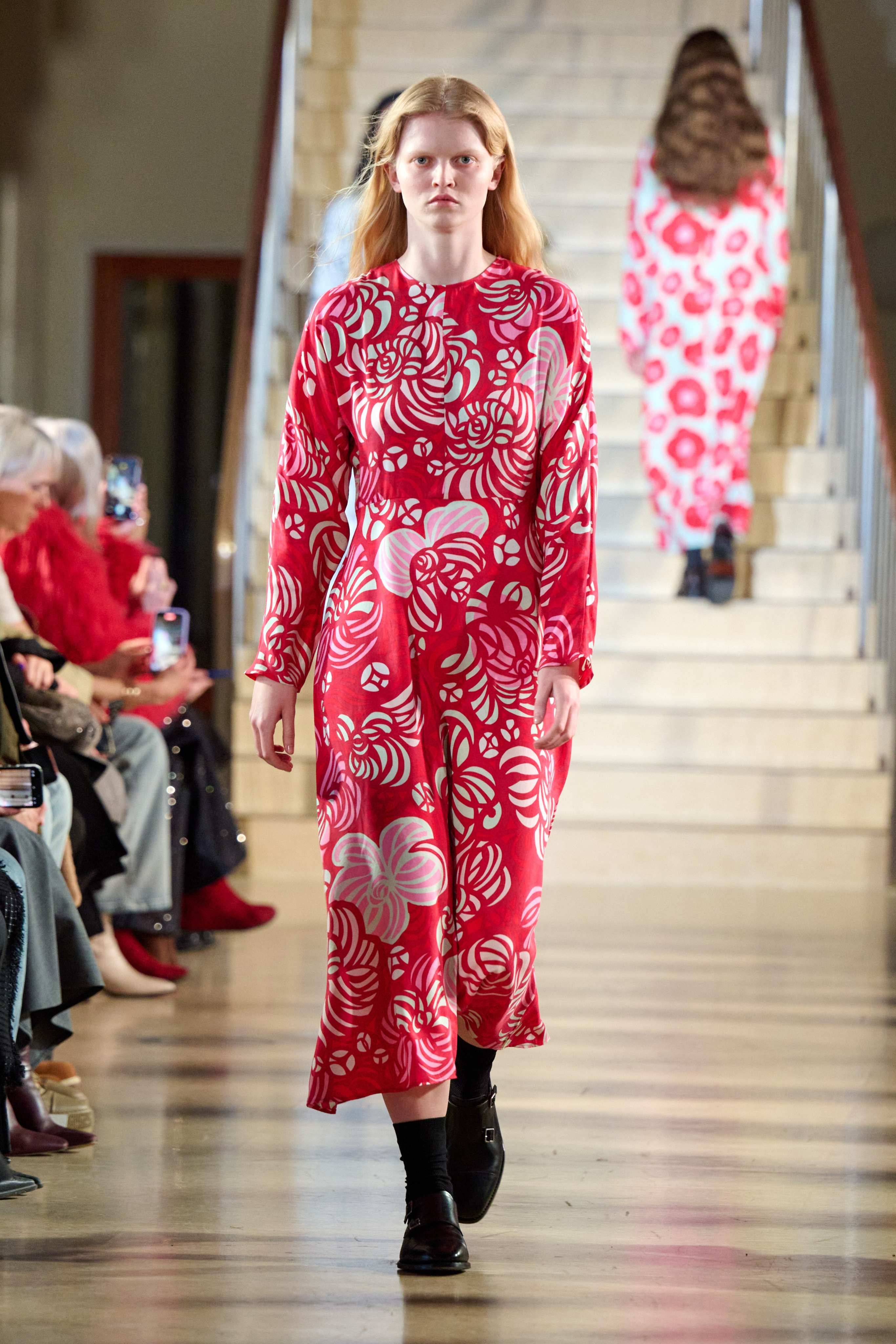 A model walks in the Marimekko fashion show wearing a long red dress