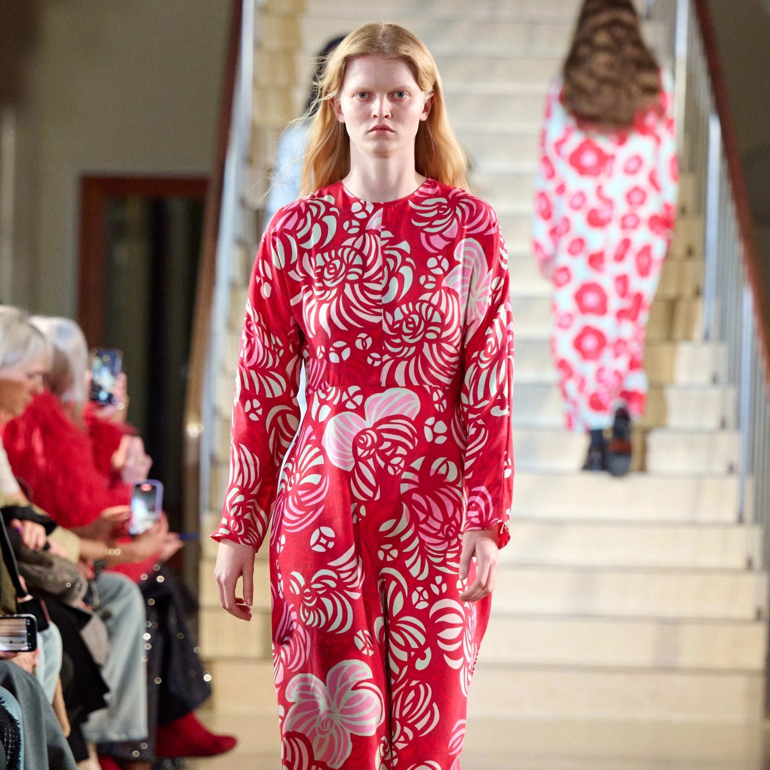 A model walks in the Marimekko fashion show wearing a long red dress