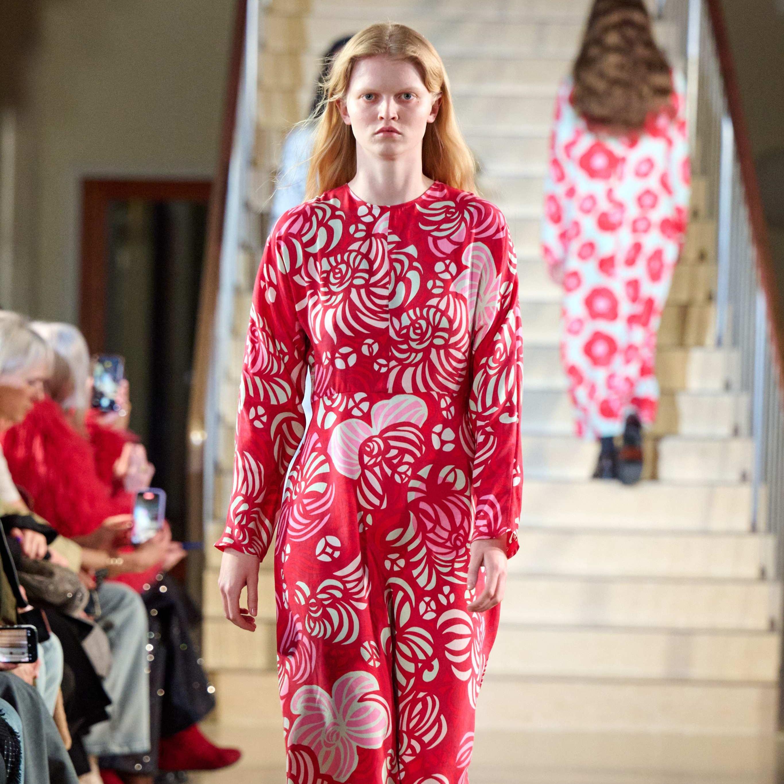 A model walks in the Marimekko fashion show wearing a long red dress