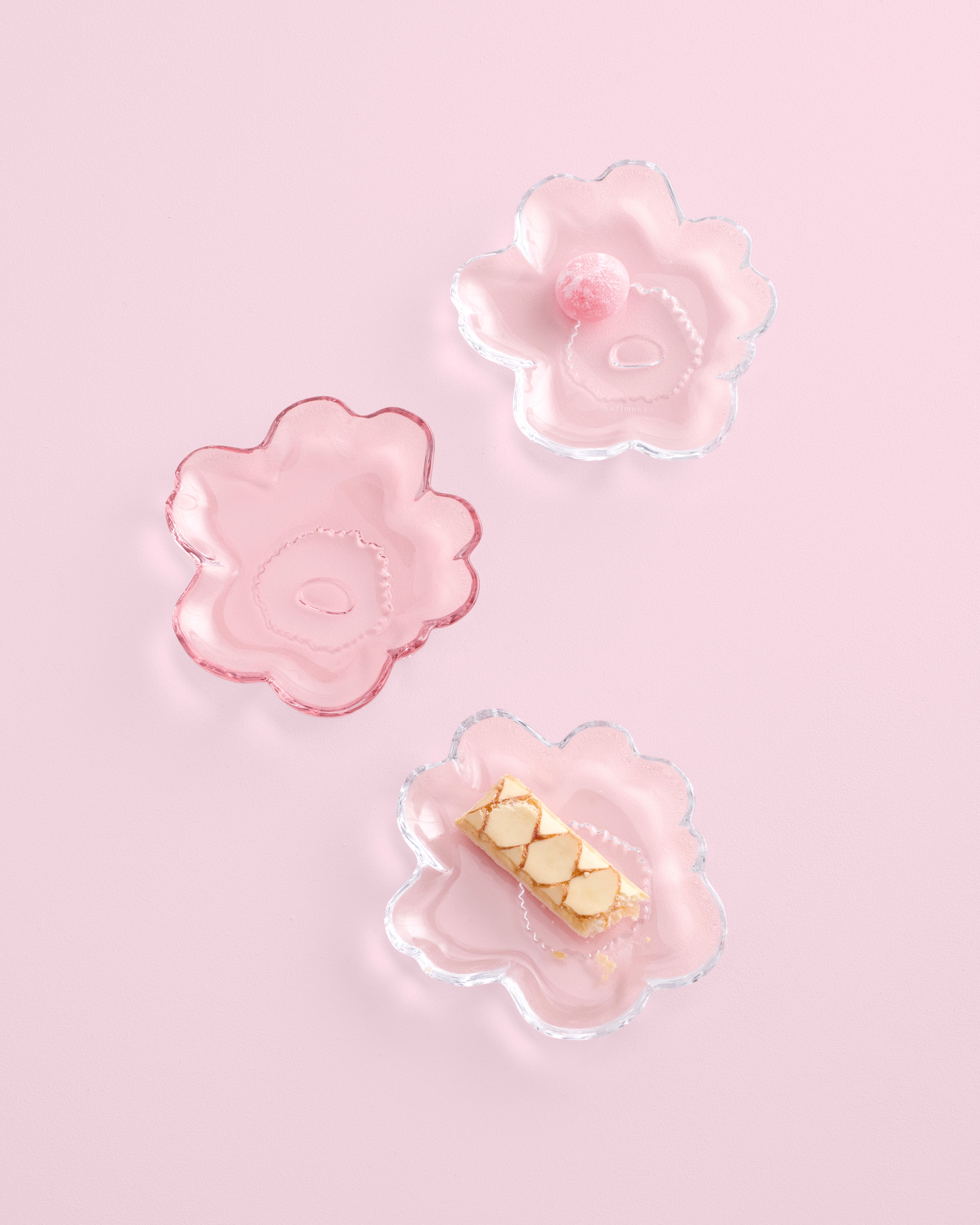 Unikko shaped glass plates on a pink table top