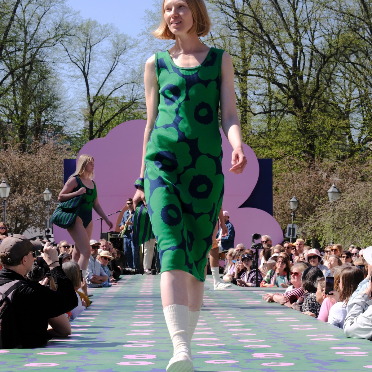 The model is dressed in a sleeveless jersey dress with a Unikko pattern.