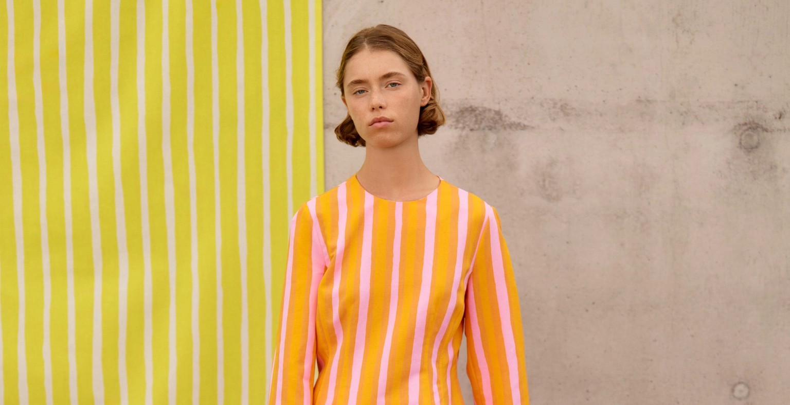 Model wearing a dress in orange Piccolo print.