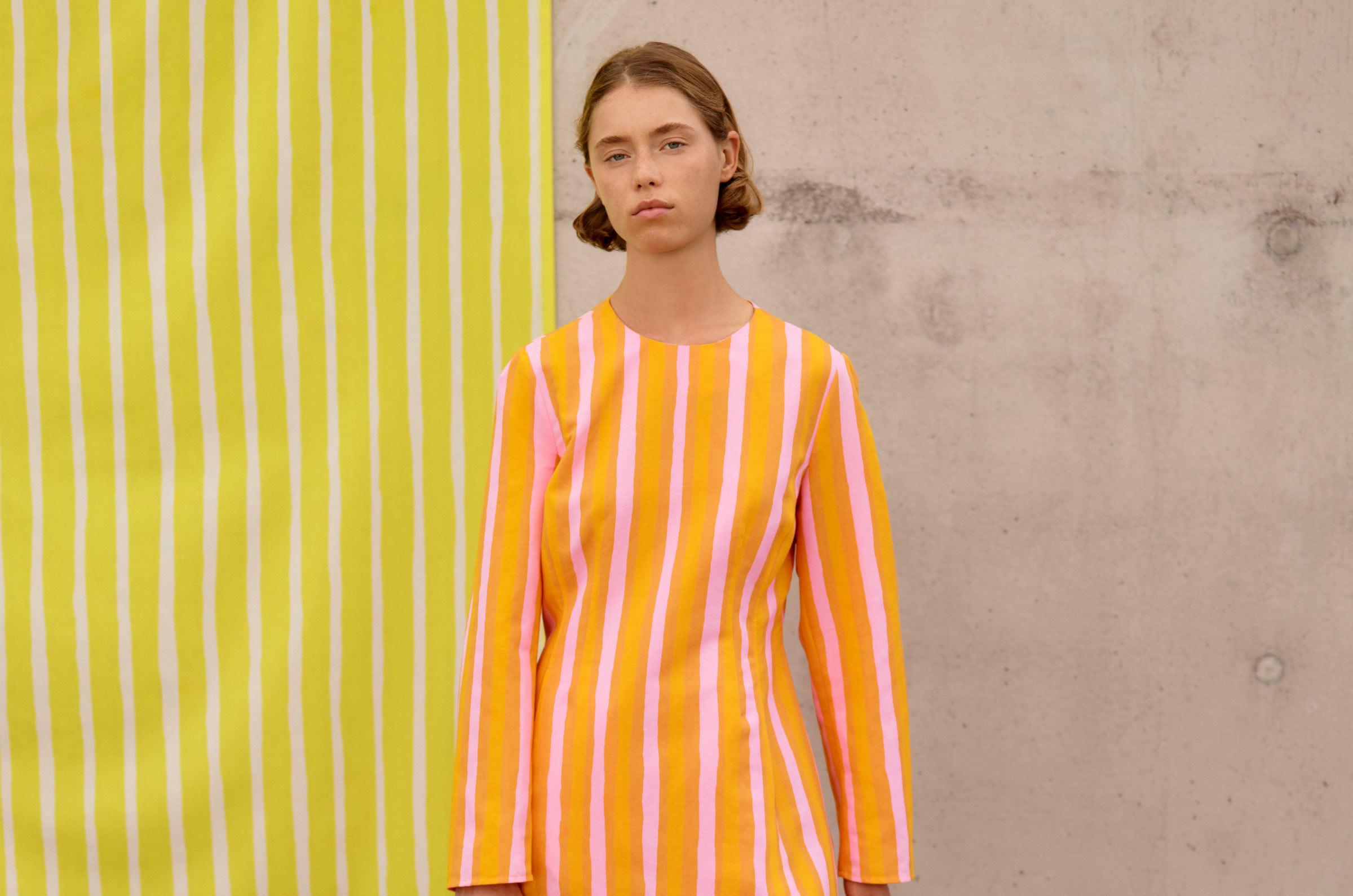 Model wearing a dress in orange Piccolo print.