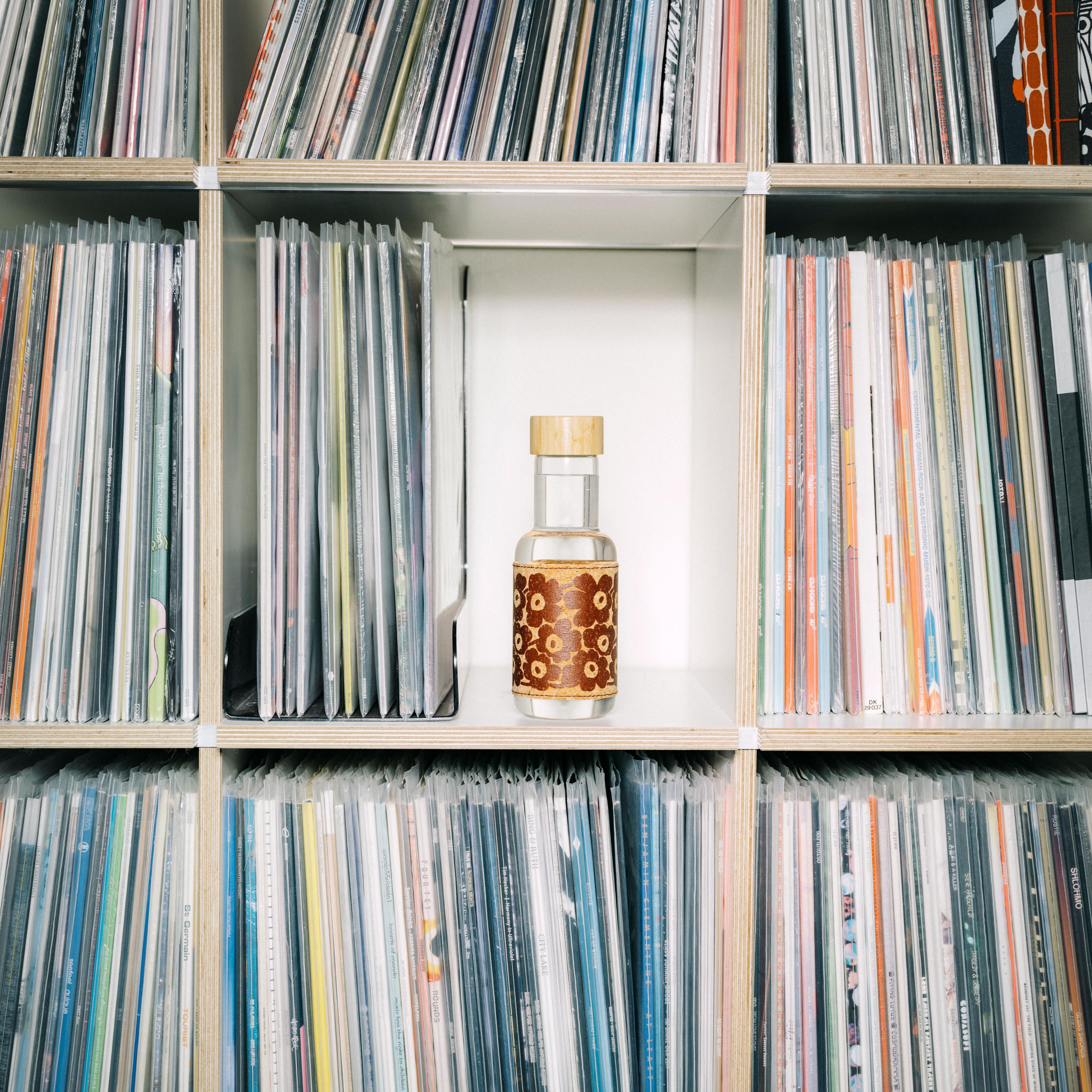 Marimade-juomapullo kirjahyllyssä vinyylilevyjen välissä.