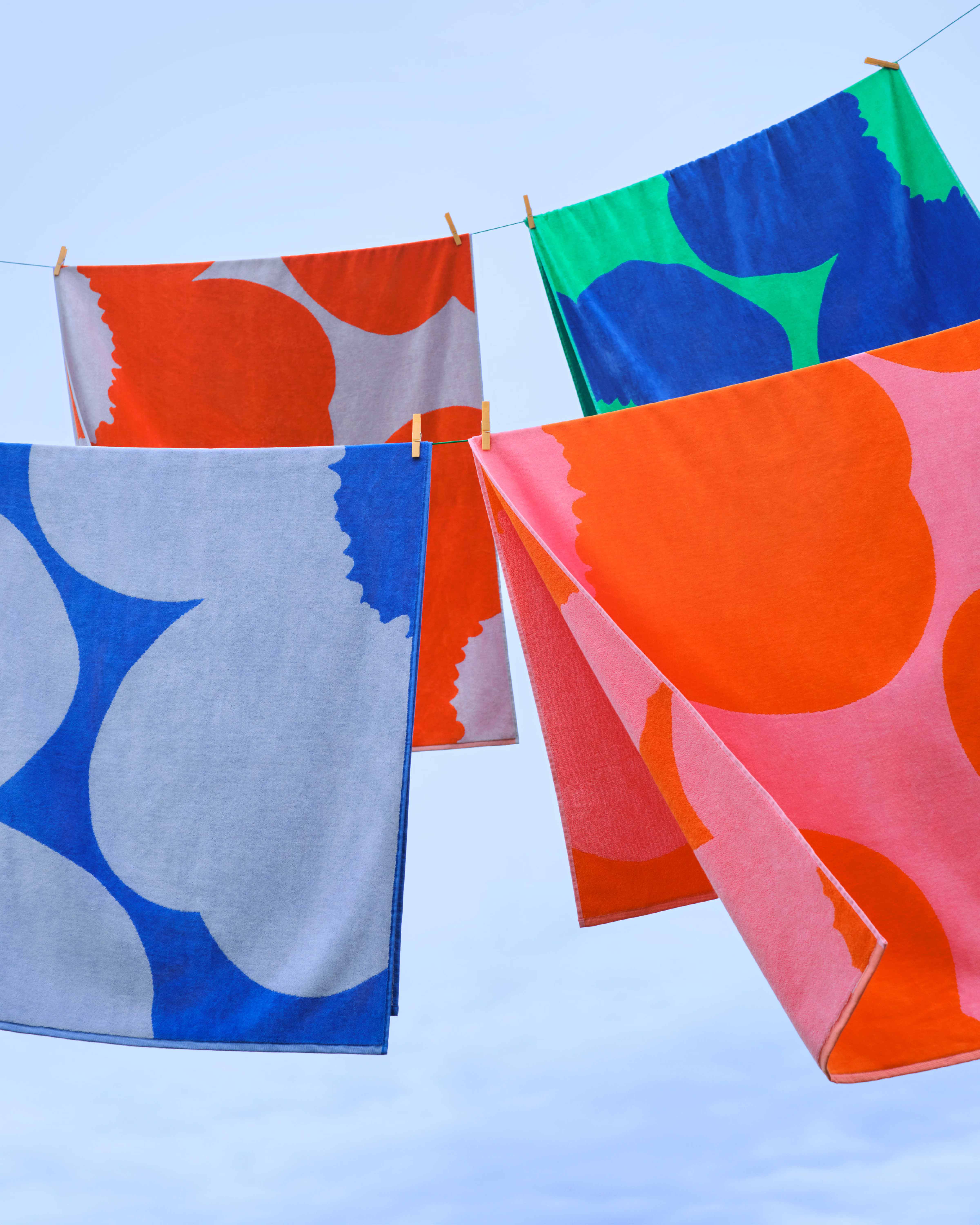 Multicolored Unikko-print towels hanging outside on a clothesline.