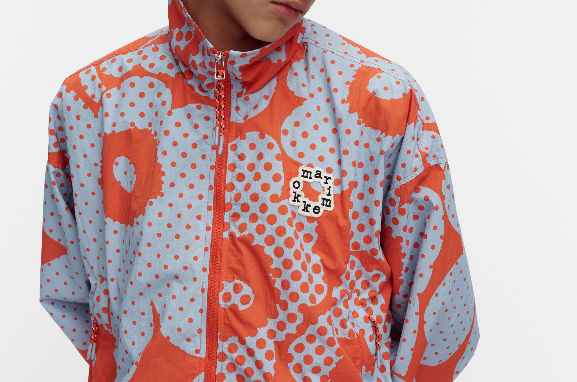 Model wearing Marimekko Kioski Active coat in red and blue Unikko print.