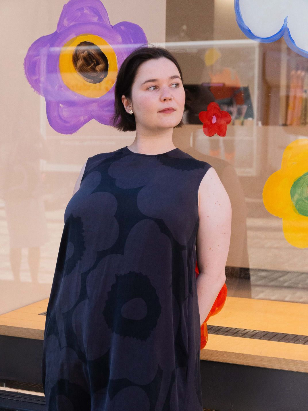 Emma Thomas posing in front of her Pride art window