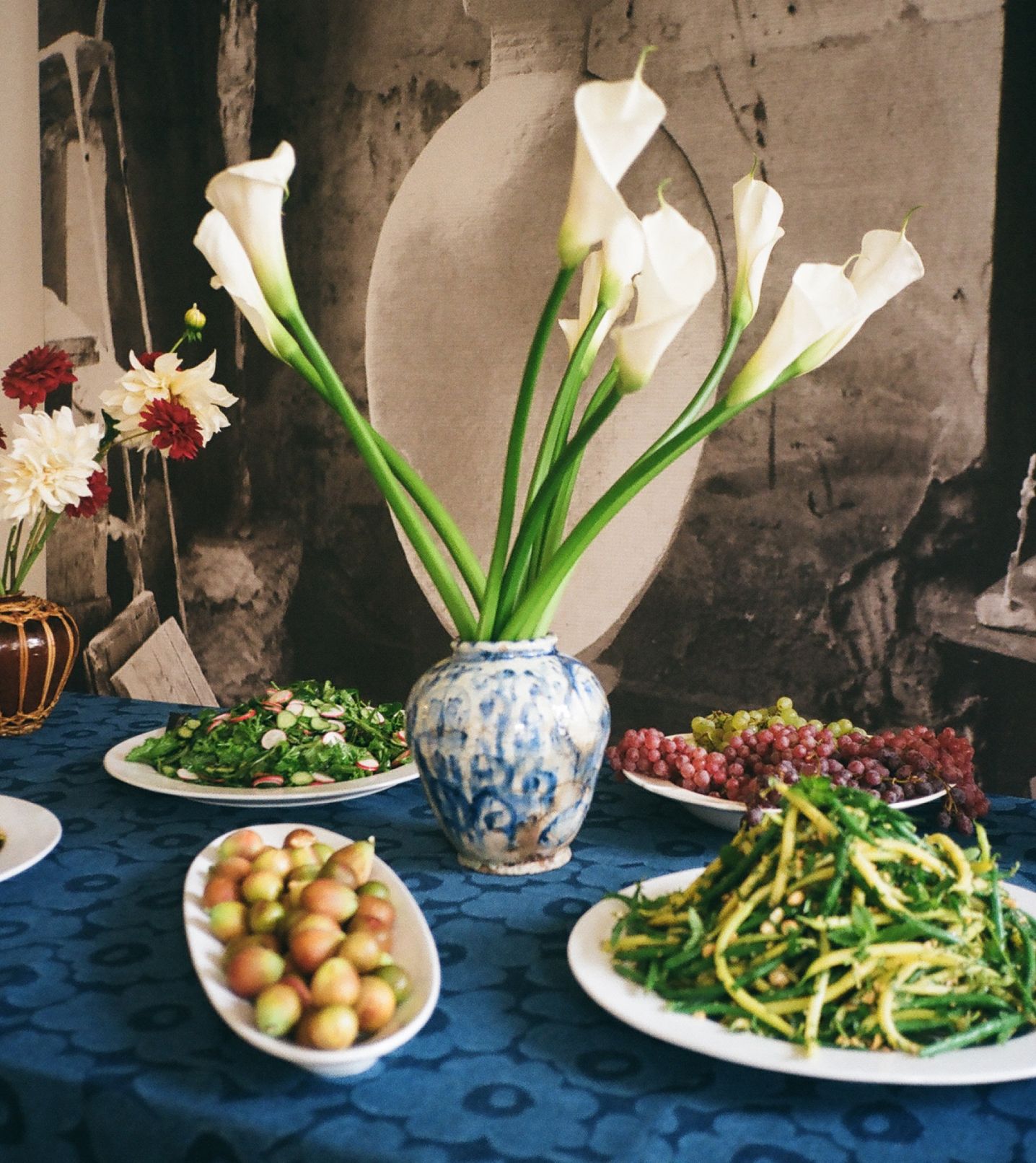 Green beans, fresh salads and fruits served at the lunch table. Tablecloth made of Maridenim fabric.