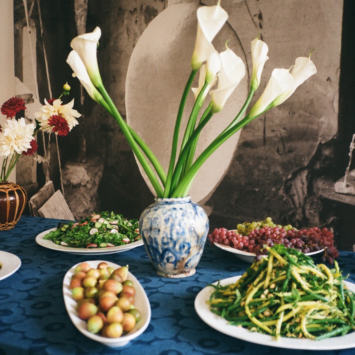 Green beans, fresh salads and fruits served at the lunch table. Tablecloth made of Maridenim fabric.