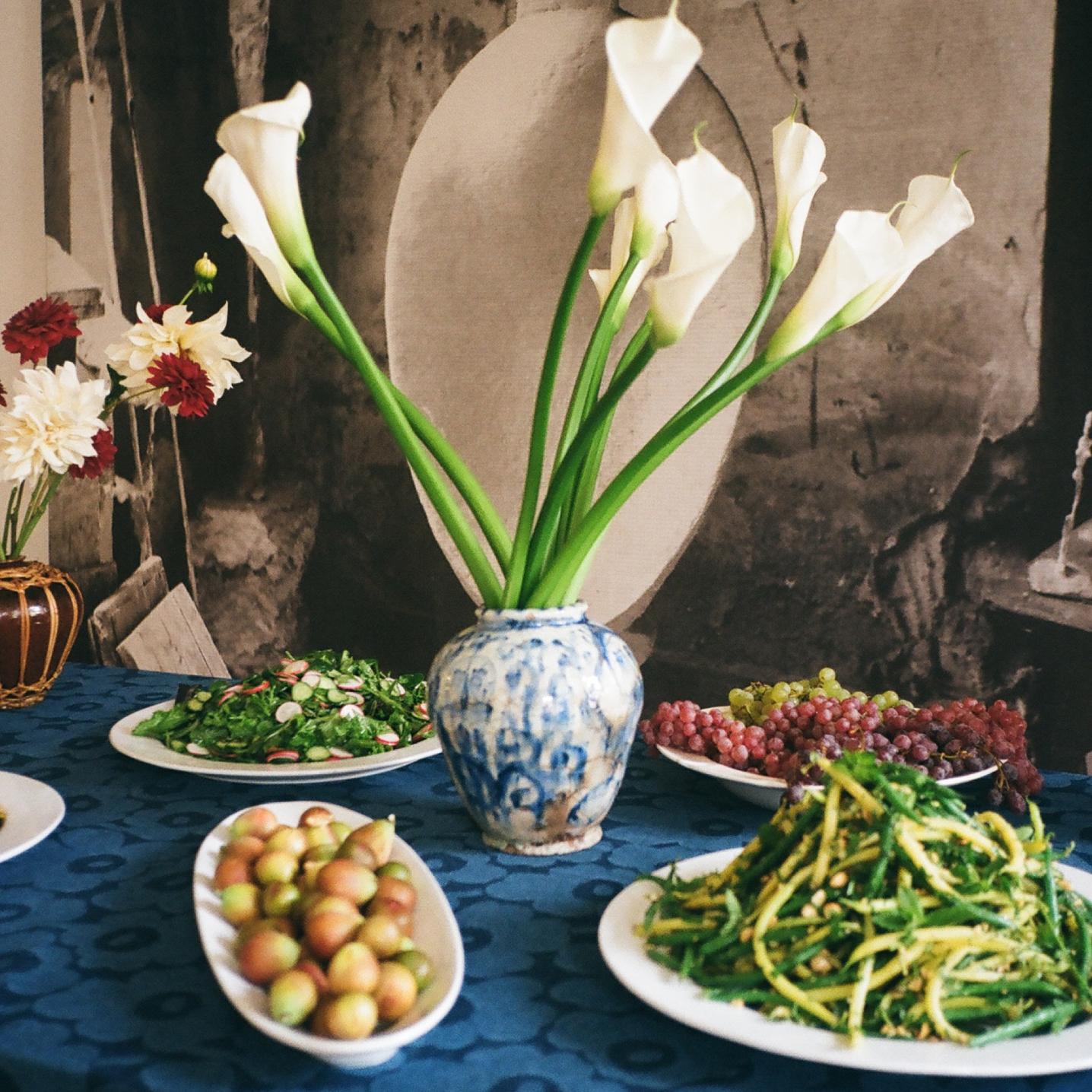 Green beans, fresh salads and fruits served at the lunch table. Tablecloth made of Maridenim fabric.