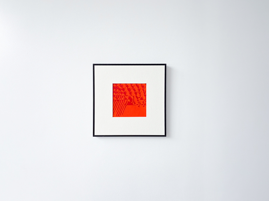Black-framed abstract art with red and orange geometric patterns on a white wall.