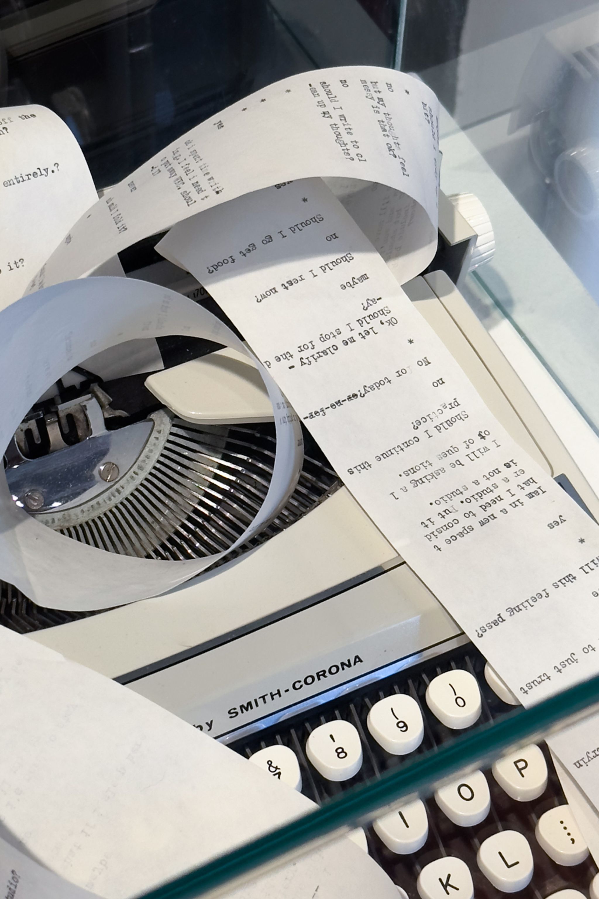 A vintage Smith-Corona typewriter with a continuous paper strip filled with typed questions and answers.