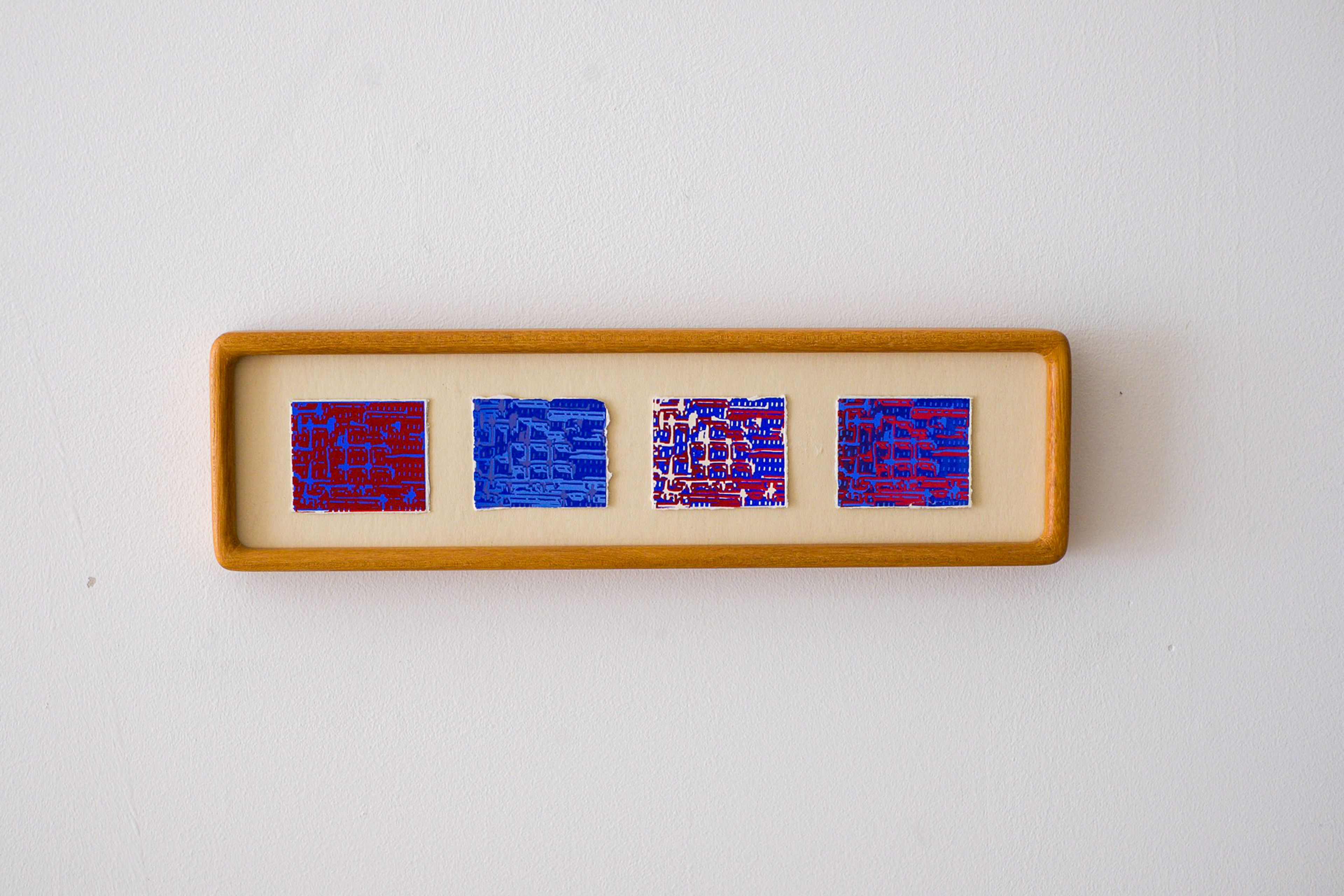 A horizontal wooden frame on a white wall holds four abstract artworks with red, blue, and white patterns.