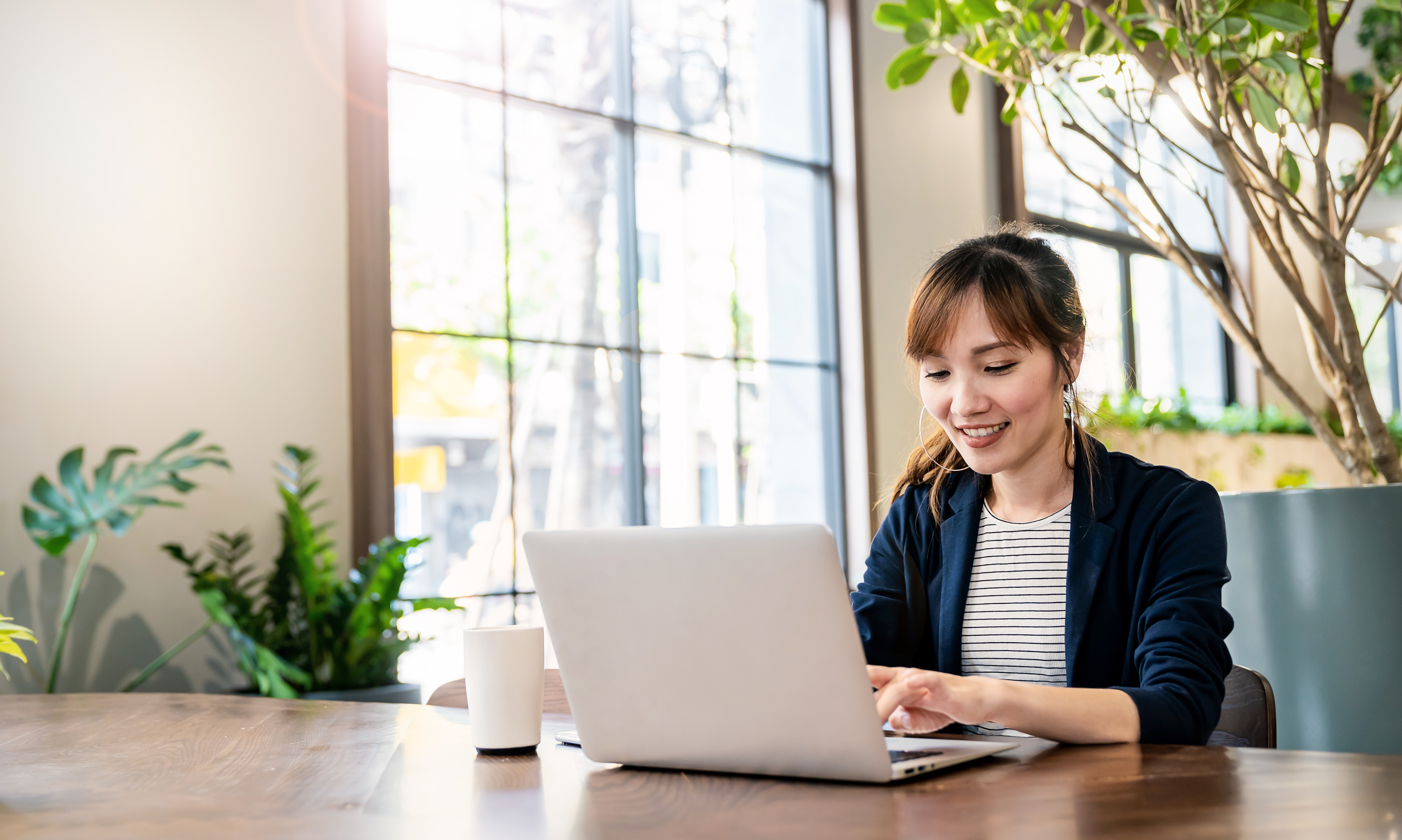 a woman is sitting at a table using a laptop computer .