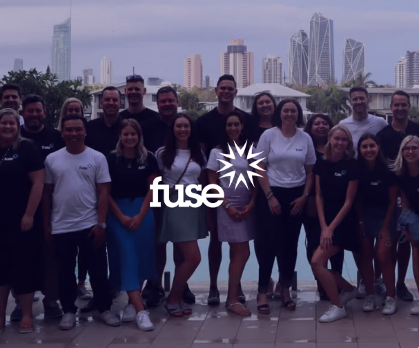 A diverse group of Fuse team members poses outdoors in front of a city skyline, with the Fuse logo overlaid.