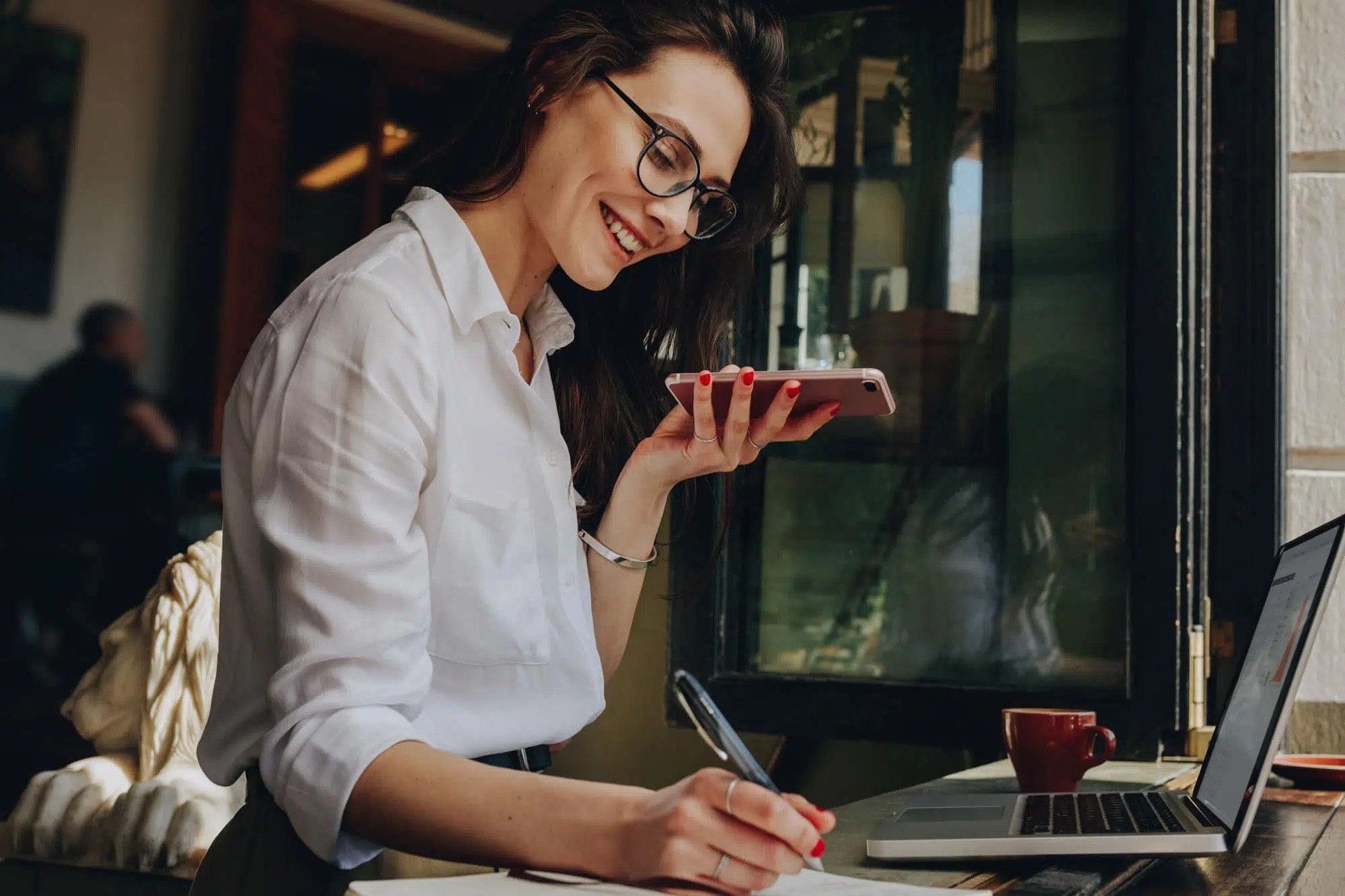 a woman is sitting at a table with a laptop and a cell phone .