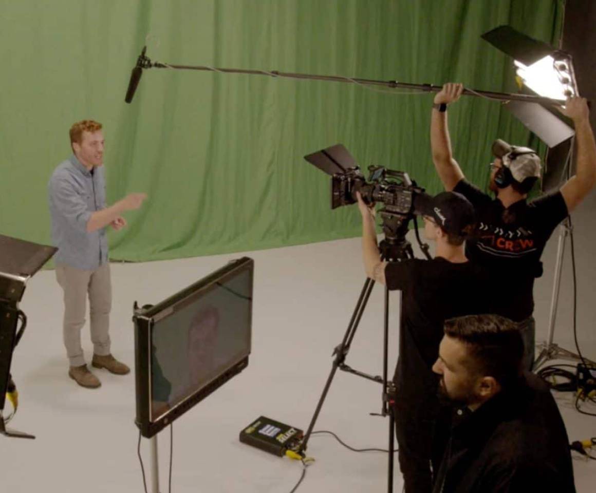A crew filming an actor in front of a green screen