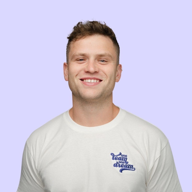 a man wearing a white t-shirt with the words `` team dream '' on it is smiling .