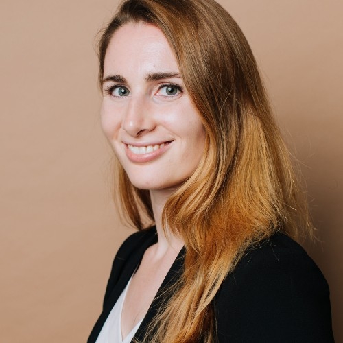 a woman with long hair is smiling and wearing a black jacket .