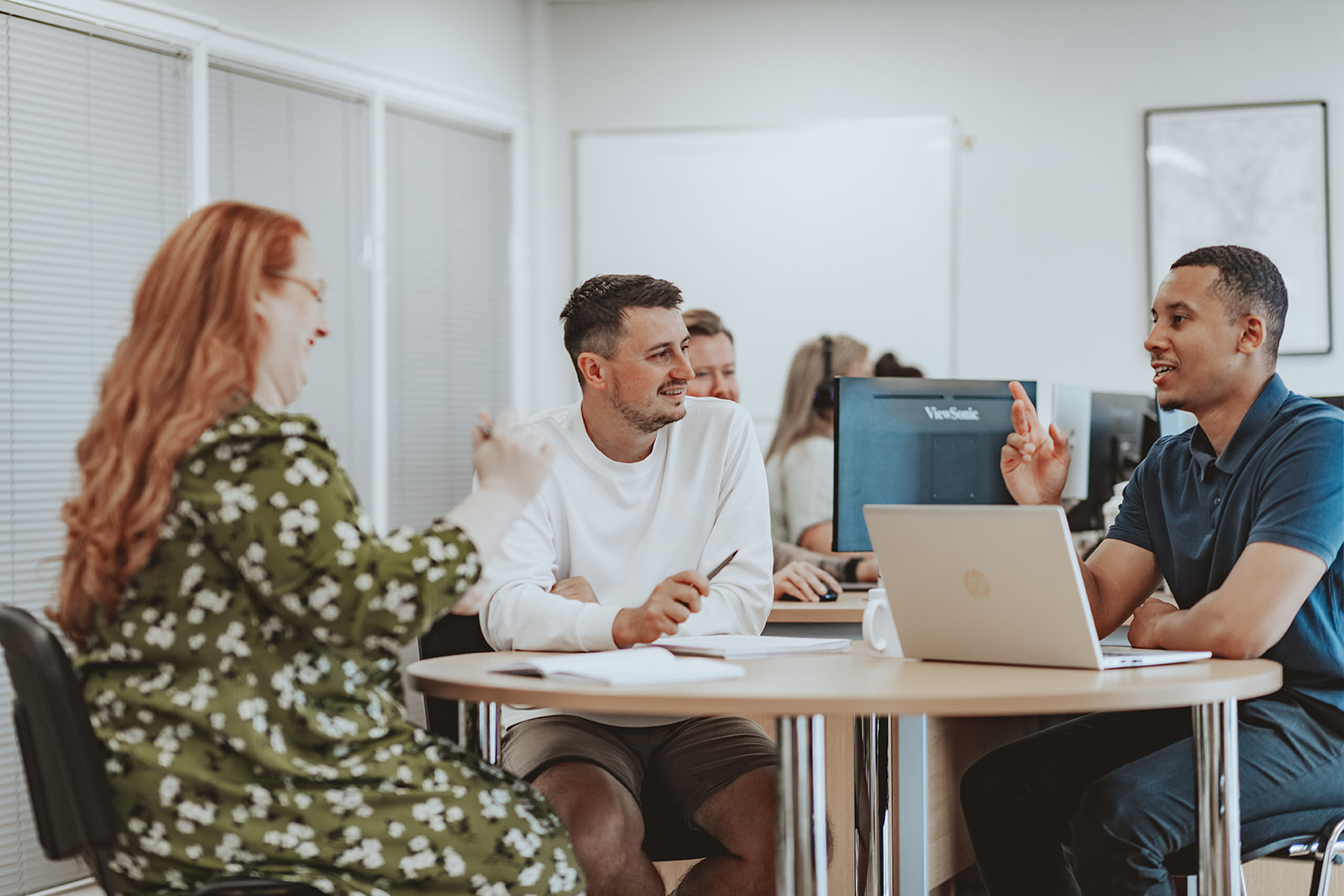 A joyful group of people and a dog raise their hands in celebration in front of a wooden building.