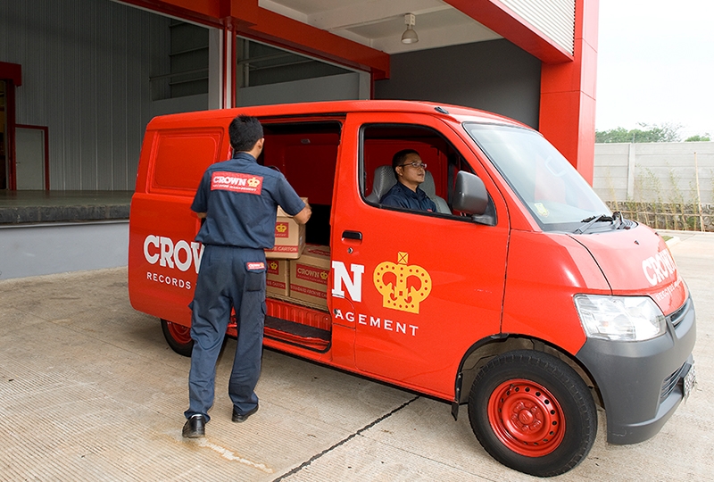 Uniformed workers loading boxes into a red Crown Records Management delivery van.