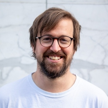 a man with a beard and glasses is smiling for the camera .