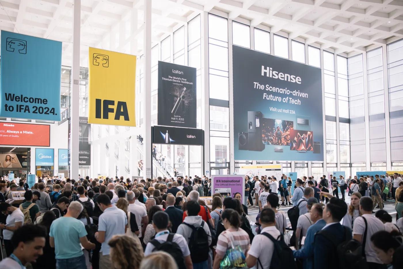 A bustling convention hall filled with attendees, with large banners for "Welcome to IFA 2024" and Hisense electronics hanging from the ceiling.