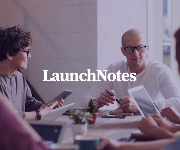 A team meeting around a table with laptops and tablets, text "LaunchNotes" displayed.