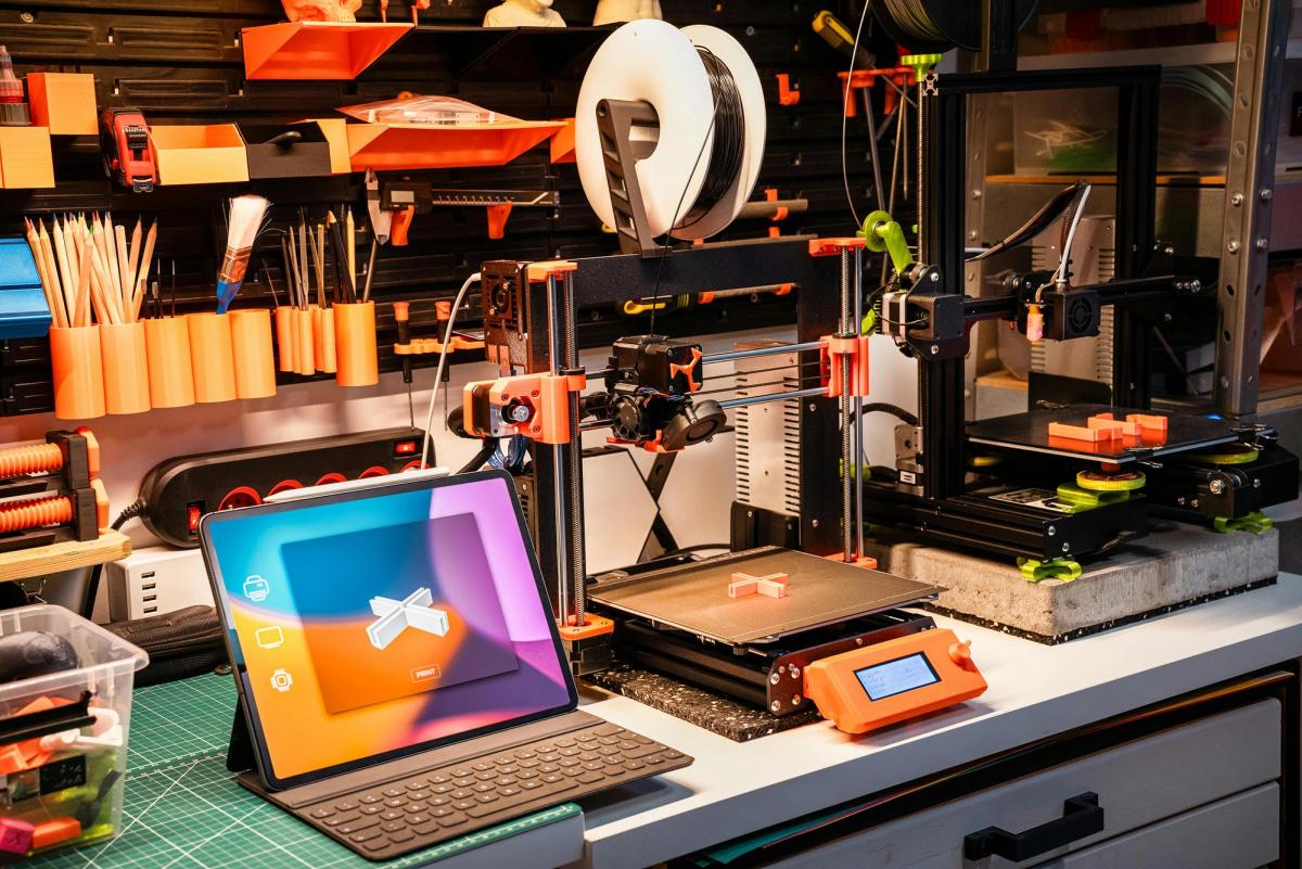 a tablet is sitting on a desk next to a 3d printer.