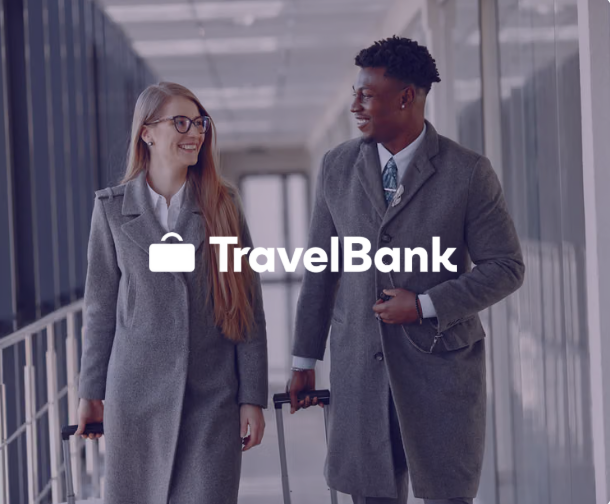TravelBank logo overlaid on a smiling man and woman walking with luggage in an airport.