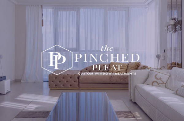 Logo for The Pinched Pleat Custom Window Treatments over a stylish living room with sheer white curtains.