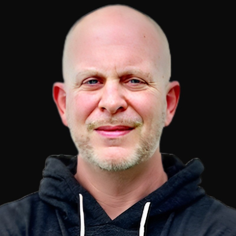 a bald man with a beard is wearing a black hoodie and smiling .