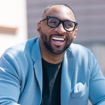 a man wearing glasses and a blue jacket is smiling .