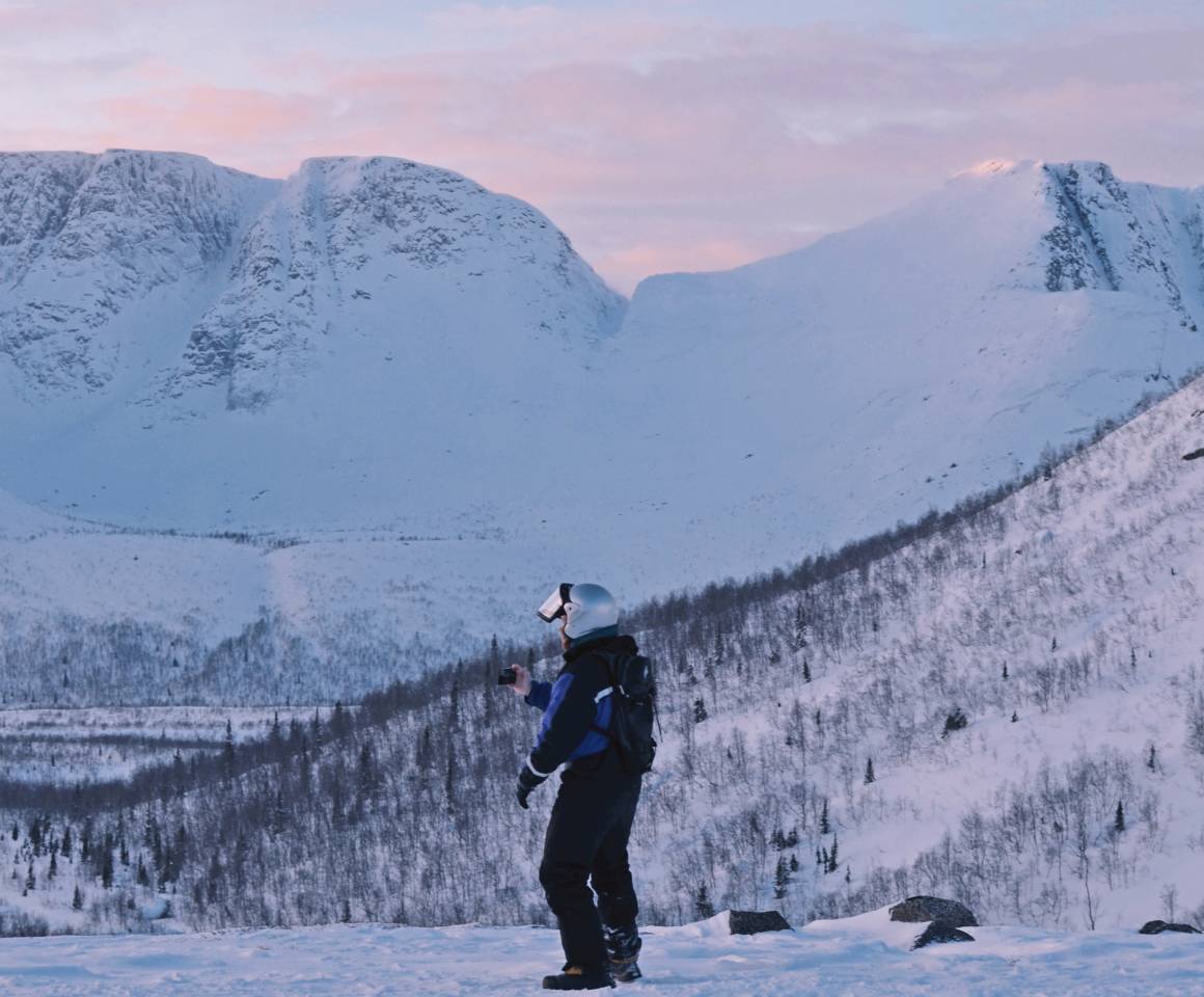 A man standing at the foot of snow covered hills