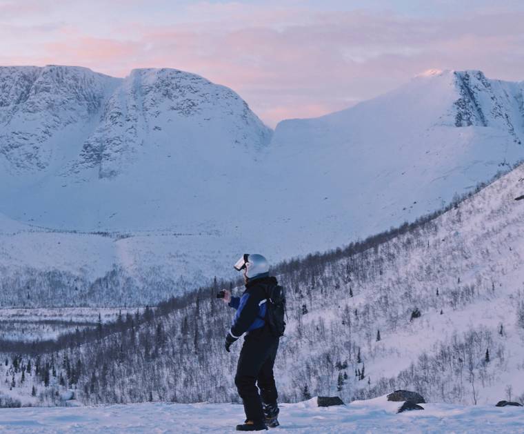 A man standing at the foot of snow covered hills