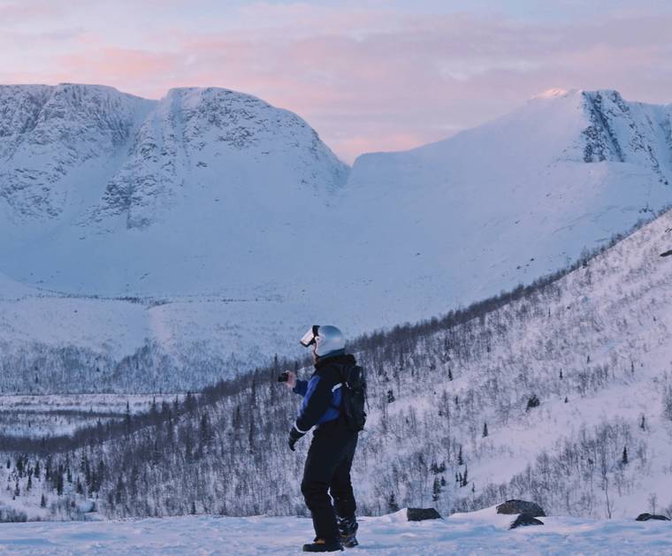 A man standing at the foot of snow covered hills