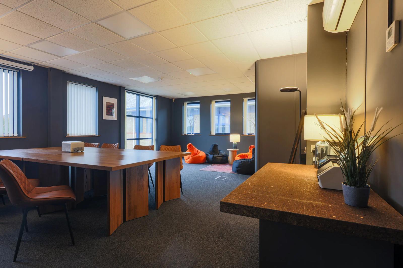 The community room: a long table, chairs and bean bags by the windows