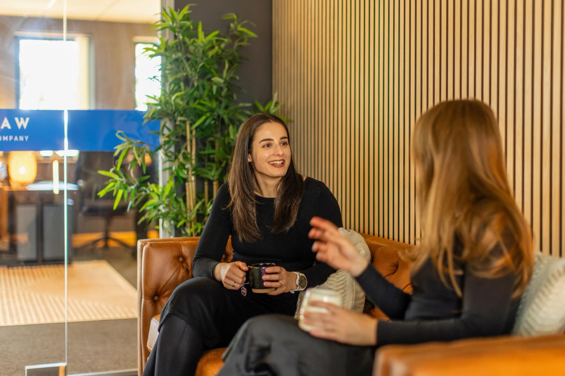 Two people talking over a hot drink on the office sofa