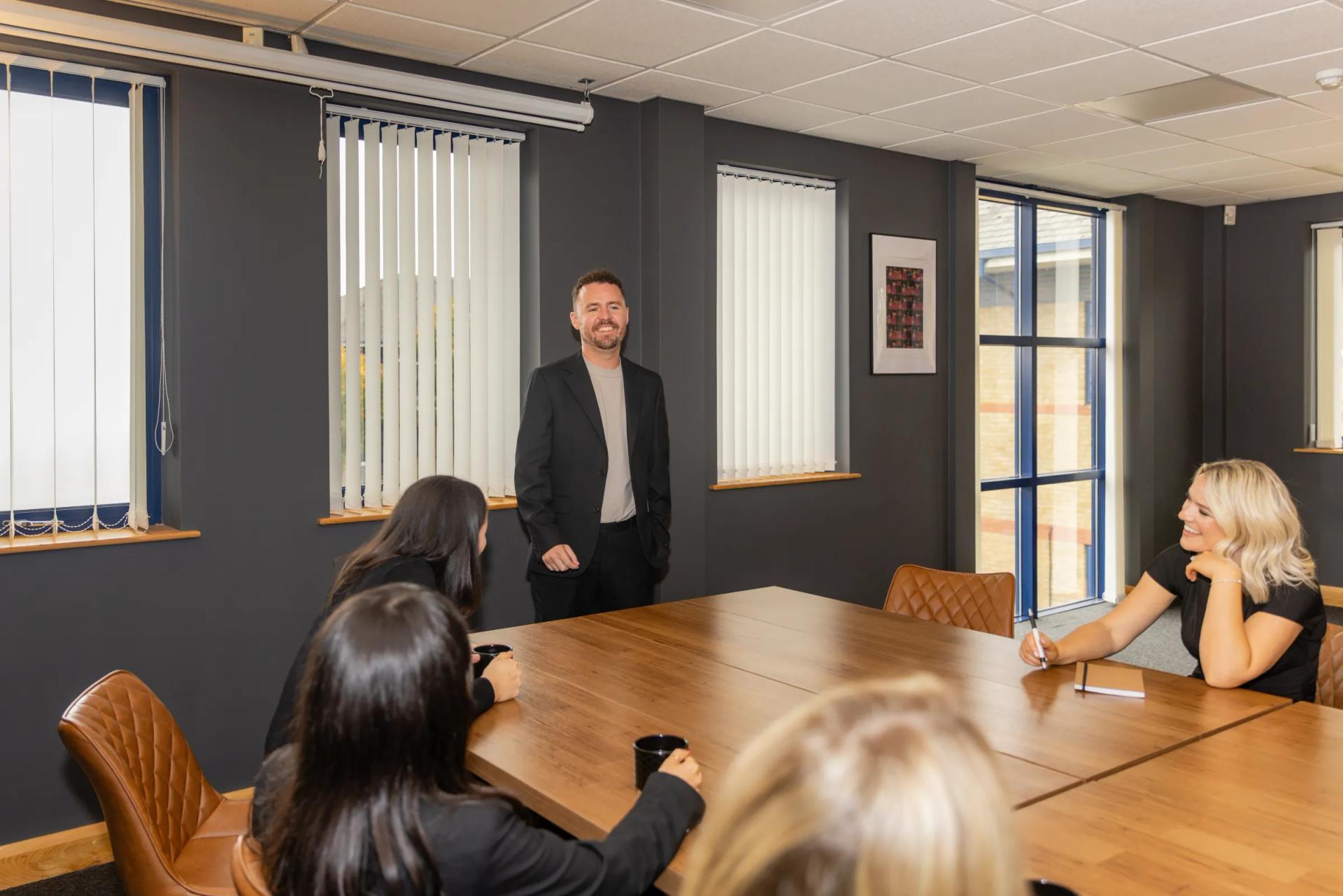 A training session: the trainer standing at the head of the long table, the group seated around it