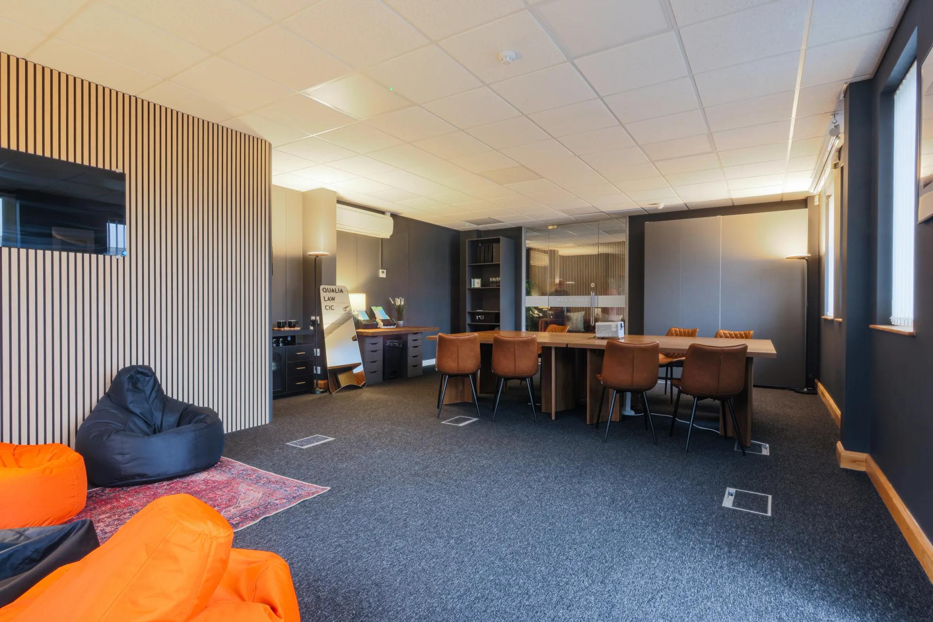 The community room: a long table and chairs, bean bags and a rug, with a screen on the wall