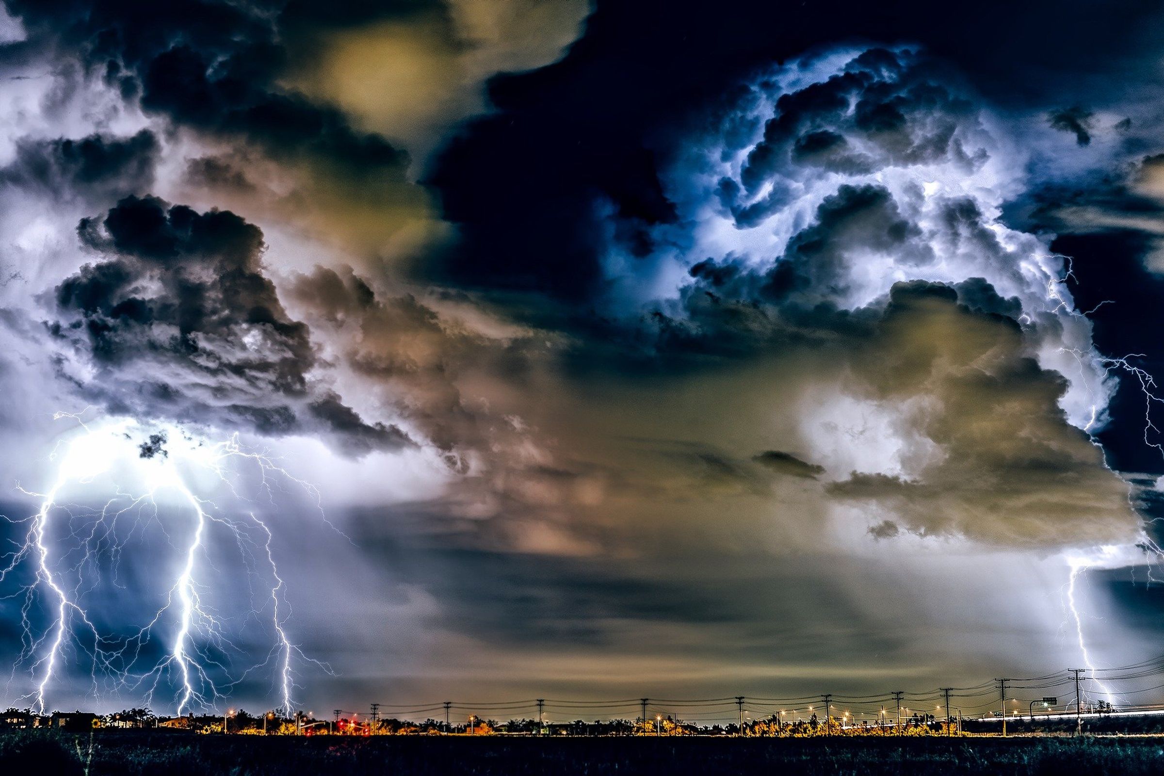 Nächtliches Gewitter mit mehreren Blitzeinschlägen über einer Industrielandschaft
